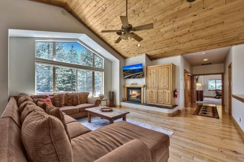 Unwind in this spacious living room where rustic wood meets modern comfort, complete with a fireplace and forest views.