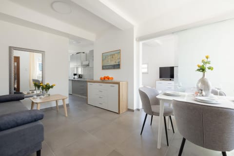 A modern, open-plan living room showcasing a well-lit area with elegant decor and a dining space in the background.
