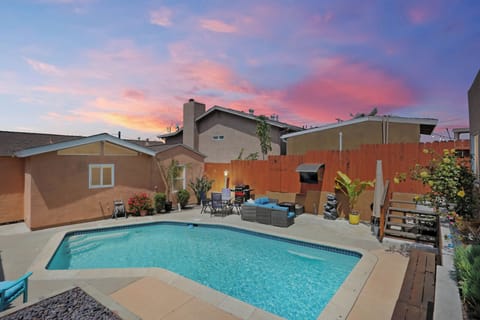 Backyard oasis with a pool, cozy lounge area, and vibrant sunset skies—perfect for relaxing.