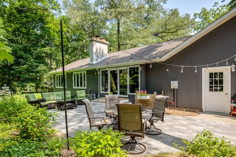Spacious backyard patio w/ outdoor dining set, surrounded by mature trees for peaceful gatherings.
