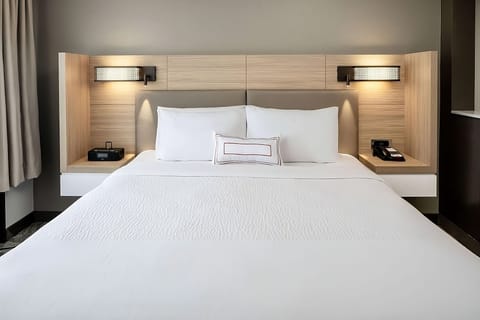 Sink into crisp linens beneath warm, calming bedside lights.