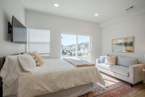 Bright bedroom with queen bed, sofa, and large windows