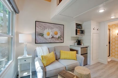 Charming tiny cottage with cozy living space, comfortable loveseat, and fully stocked kitchenette | relax with a book or a show, surrounded by natural light and soothing decor, ideal for couples or solo travelers looking for a peaceful getaway.