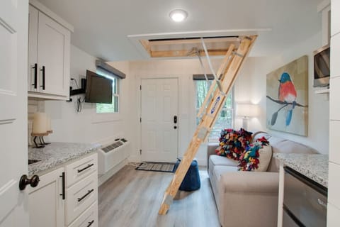 Charming living space with loft bedroom access, comfortable seating, and a wall-mounted TV | features natural light, modern amenities, and a fully equipped kitchenette ideal for a relaxing and convenient stay.