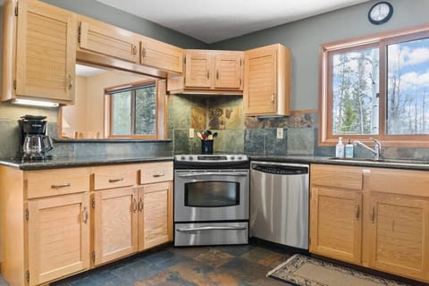 The fully equipped kitchen features a pass-through window to the dining room, stainless steel appliances, spacious countertops, and all the cookware needed to whip up a delicious meal.