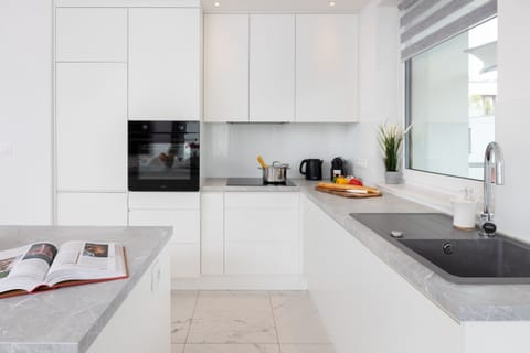 A compact and functional kitchen area, featuring modern appliances and a clean, white design. An island table adds convenience for food preparation or casual dining.