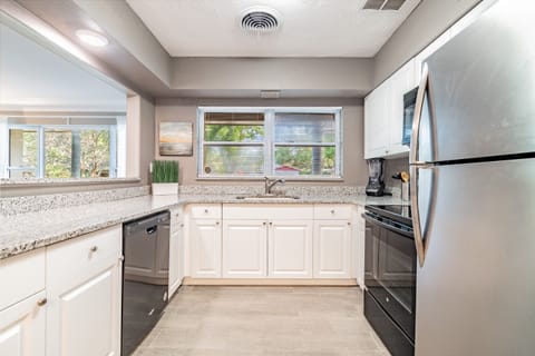 The kitchen is a masterpiece of sleek, modern design, boasting a sophisticated silver, black, and white color scheme.