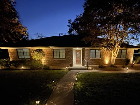 Front of house with beautiful lighting and landscaping.