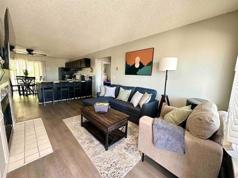 Unwind in this thoughtfully designed living space featuring a spacious sectional, elegant accent chair, and rustic wooden coffee table. The neutral tones, modern artwork, and warm lighting create a cozy yet sophisticated atmosphere.
