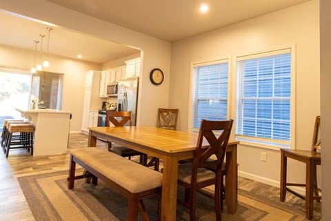 Gather for meals or game nights in the spacious dining area at Harbor Pointe, featuring a large wooden table with seating for the whole group. The open layout flows directly into the modern kitchen, making it easy to cook, dine, and connect together