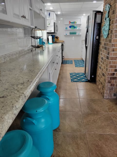 Extended open kitchen area with barstools and counter to sit and eat