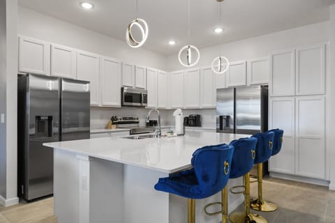 Bright gourmet kitchen with double fridges, quartz counters, and luxe velvet stools