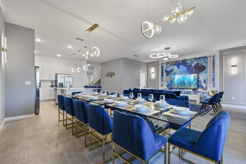 Chic open-concept dining and lounge with ocean mural, velvet chairs, and glam vibes