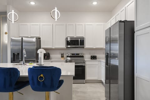 Modern chef’s kitchen with sleek appliances, bright cabinetry, and stylish seating