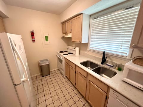 The functional galley kitchen provides a full stove, double sink, and views of the neighborhood greenery.