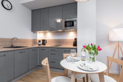 A modern kitchenette with grey cabinetry, wooden countertops, and high-quality appliances for a practical setup.
