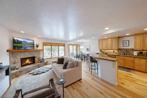 This spacious living room features a cozy fireplace and large windows offering scenic mountain views. Relax on the comfortable sectional while enjoying the tranquil atmosphere.