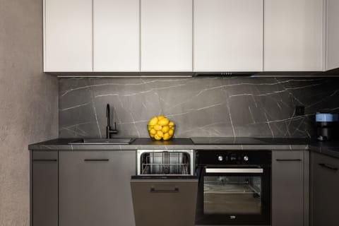 A sleek kitchen with dark cabinets, a built-in oven, and a modern backsplash.