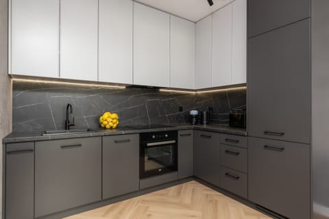 A sleek kitchen with dark cabinets, a built-in oven, and a modern backsplash.