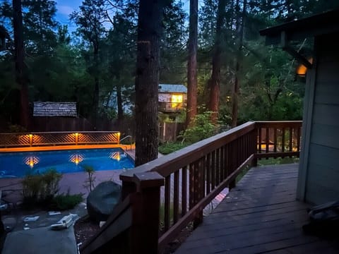 Spacious fenced-in backyard with in-ground pool, large wraparound deck, multiple outdoor seating areas.