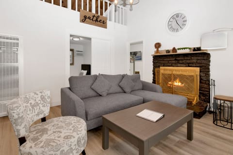 Cozy mountain living room with a stone fireplace, comfy seating, and smart TV—perfect for relaxing evenings, movie nights, and warm cabin vibes after outdoor adventures.