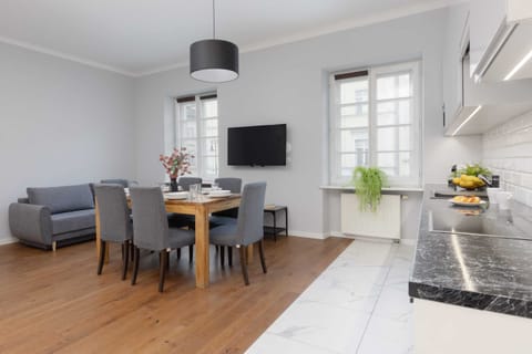 A spacious and bright living area featuring a gray sofa, wooden floors, and modern decor, creating a cozy and inviting atmosphere.