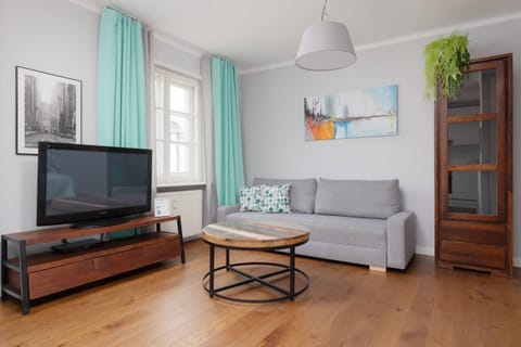 A spacious and bright living area with turquoise accents, a comfortable sofa, a coffee table, and a TV, perfect for relaxation.