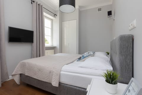 A cozy and modern studio with a double bed, a gray upholstered headboard, and neutral decor that creates a welcoming atmosphere.