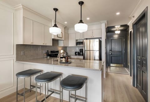 the luxurious kitchen has an electric stove, full fridge, and a microwave.