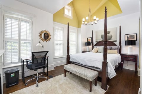 Large master bedroom with featuring high ceilings, a luxurious queen-size bed, a dedicated workstation and a en-suite master bathroom.