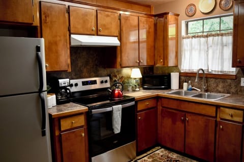 Kitchen with electric stove and fridge. Coffee pot. 
NO dishwasher.
