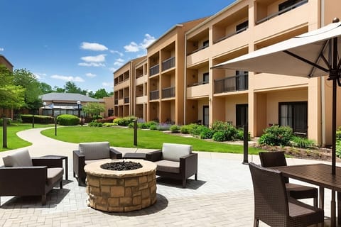 Gather around the fire pit under sunny, landscaped courtyard skies.