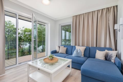 Spacious living room with a comfortable blue sofa, a coffee table, and large glass doors leading to a balcony.