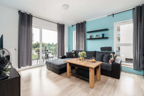 Bright and spacious living room featuring a comfortable gray sofa, wooden coffee table, and a large window.


