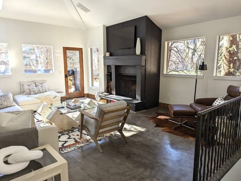 Bright light living area with wood burning fireplace and deck with hot tub.
