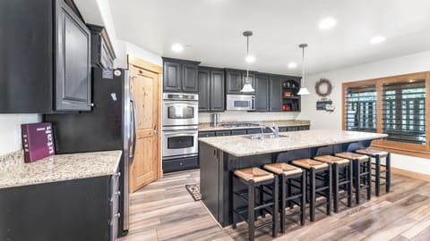- Spacious kitchen with double ovens and plenty of cabinet storage  
- Long granite island with seating perfect for shared meals and drinks  
- Modern lighting and open space make cooking a social experience
