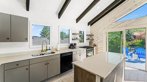 - Modern kitchen with sleek cabinetry and stone counters  
- Island seating for meals and conversation while cooking  
- Large windows and patio door bring in mountain scenery