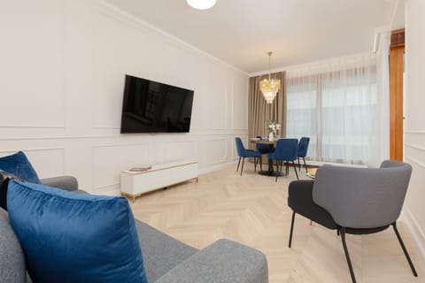 Spacious living room with a modern sofa, armchair, flat-screen TV, and elegant decor.

