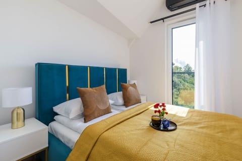 Stylish bedroom with a vibrant blue headboard, yellow bedding, and a bright, airy ambiance.

