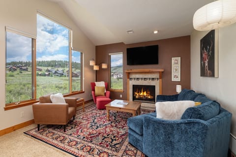 Unwind by your crackling fireplace with sweeping mountain views through floor-to-ceiling windows in this cozy living space.