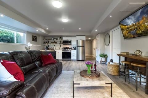 Your whole ground floor, lit and waiting — reclining leather sofa, smart TV, and a bottle already open on the tray. This is where a Fall Release Saturday ends.