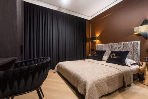 A stylish bedroom with black curtains, a large bed, and warm lighting creating a cozy, modern vibe.

