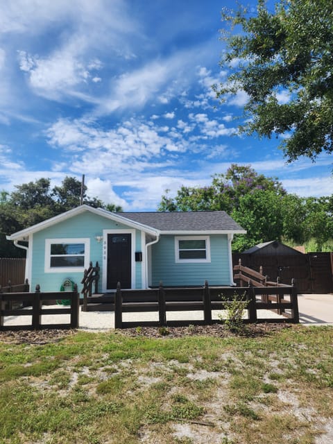 Charming teal home with fenced yard, brown deck,  large parking area, and camera