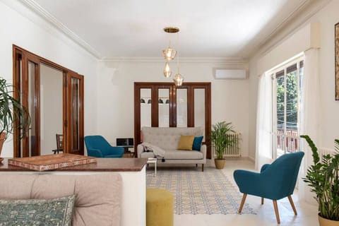 A bright and beautifully proportioned reception space. The open layout seamlessly connects comfortable lounge zones, highlighted by rich wood-framed glass doors and vibrant teal accent seating.