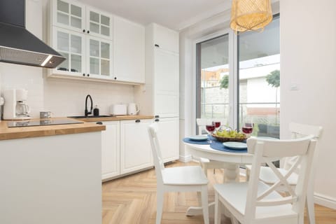 A modern kitchen with white cabinets, wooden countertops, and a dining area by the window.