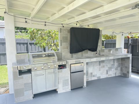 Outdoor kitchen with 4 burner grill, outdoor mini-fridge, TV, and out door lighting.