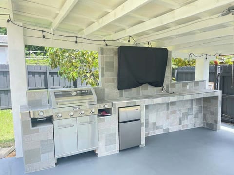 Outdoor kitchen with 4 burner grill, outdoor mini-fridge, TV, and out door lighting. 