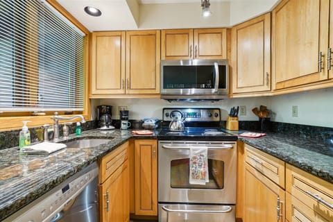 Fully equipped kitchen with stainless-steel appliances, granite countertops, and all essentials for meal prep — conveniently open to the dining and living areas.