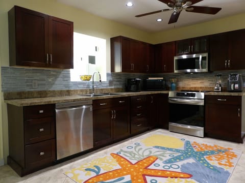 Kitchen w/ look thru to game rm, cleaning supplies, Keurig coffee pot & pod.