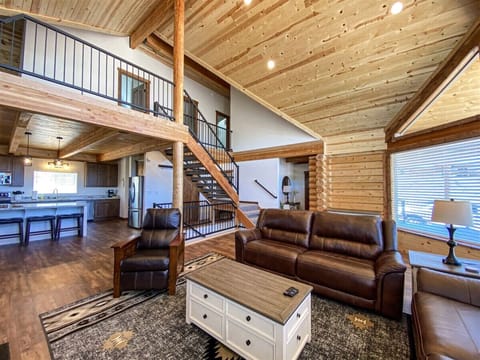 Spacious cabin great room with cozy leather seating, vaulted ceilings, and an open kitchen layout.